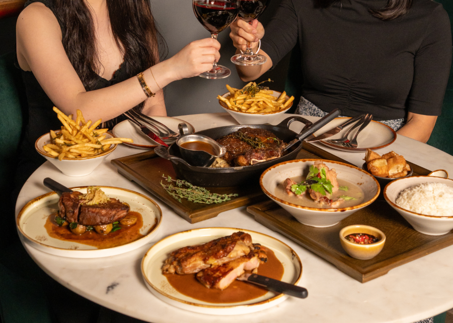 Best cocktail bars in Singapore - Alleybar people toasting with wine with a delectable food spread