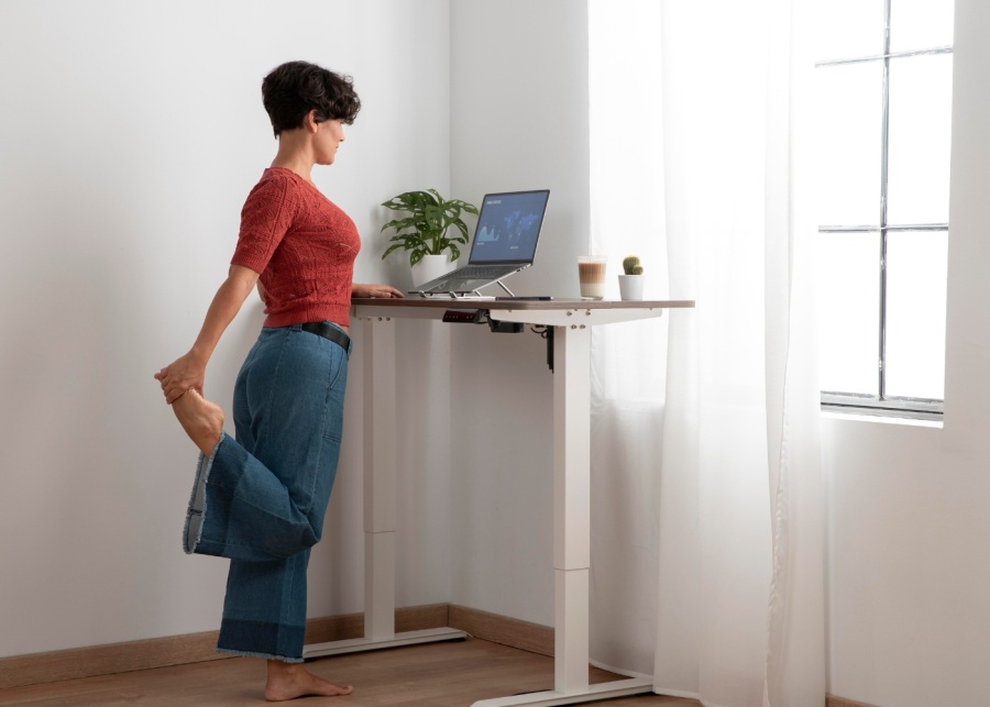 Oxford Spine and Neurosurgery Centre - Back pain - Woman stretching while working from a standing desk