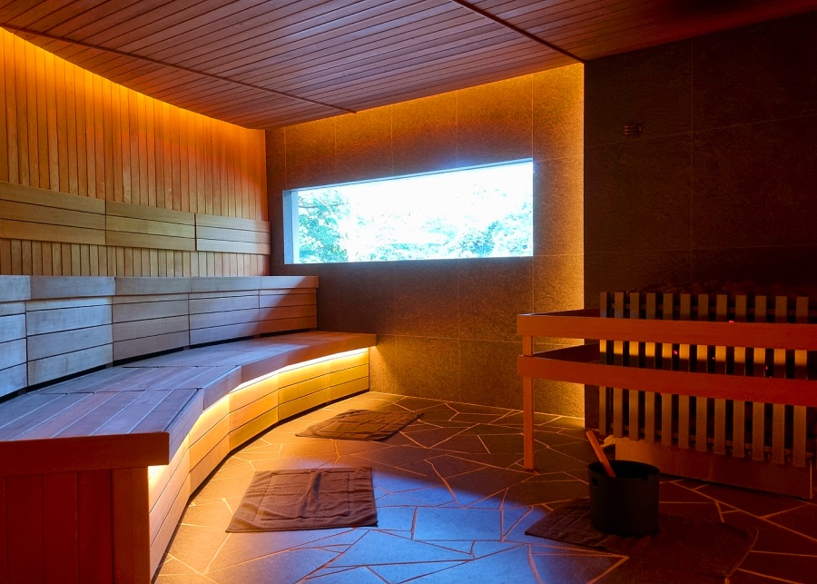 Nowhere Baths' sauna with tiered wooden benches and a window looking out into the lush greenery