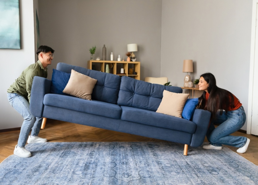 First-time home buyer mistakes - Couple shifting a sofa into their new home