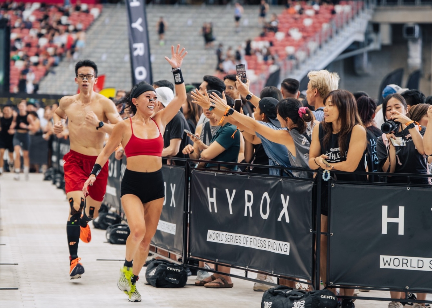 Hyrox events in Singapore and Asia-Pacific 2026 - Female participant running and waving to spectators