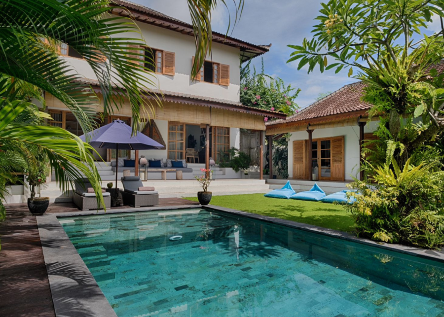 Private pool and tropical garden at Maya Villa Canggu featuring a spacious outdoor lounge and traditional Balinese-style villa buildings.