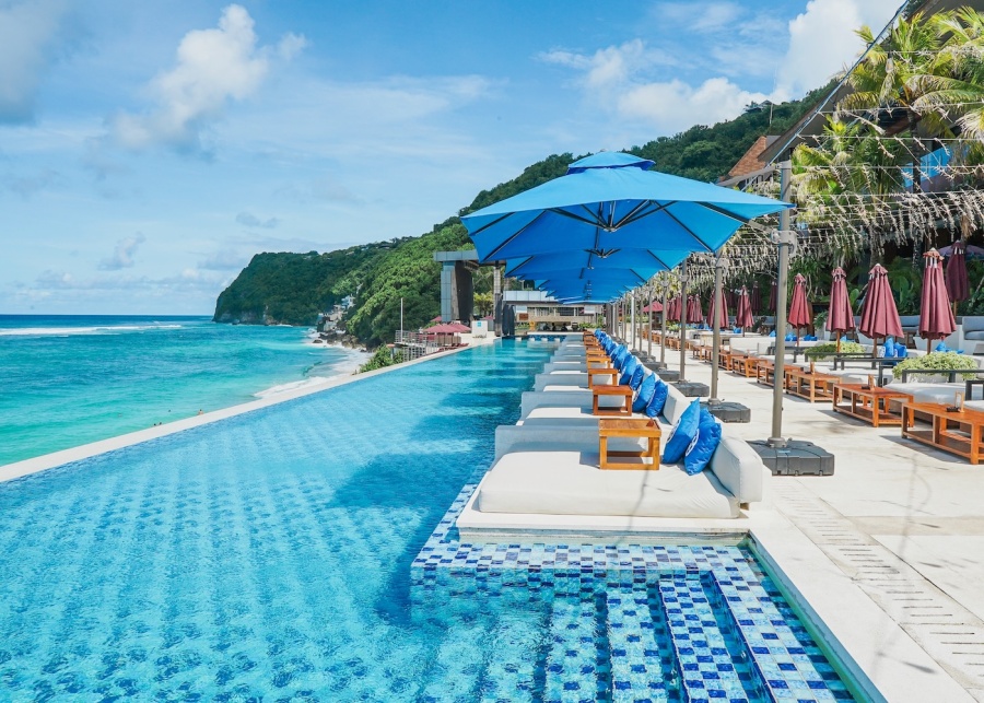 The infinity pool and ocean-view cabanas at White Rock Beach Club, overlooking Melasti Beach in South Bali, Indonesia