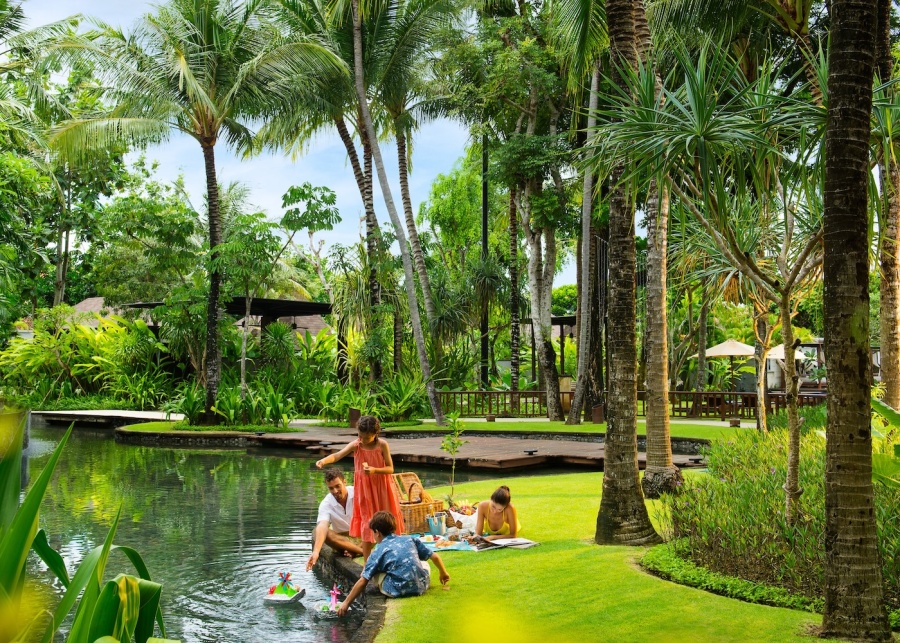 Family enjoying a picnic by a pond at Conrad Bali - a family friendly resort in Nusa Dua, Bali, Indonesia