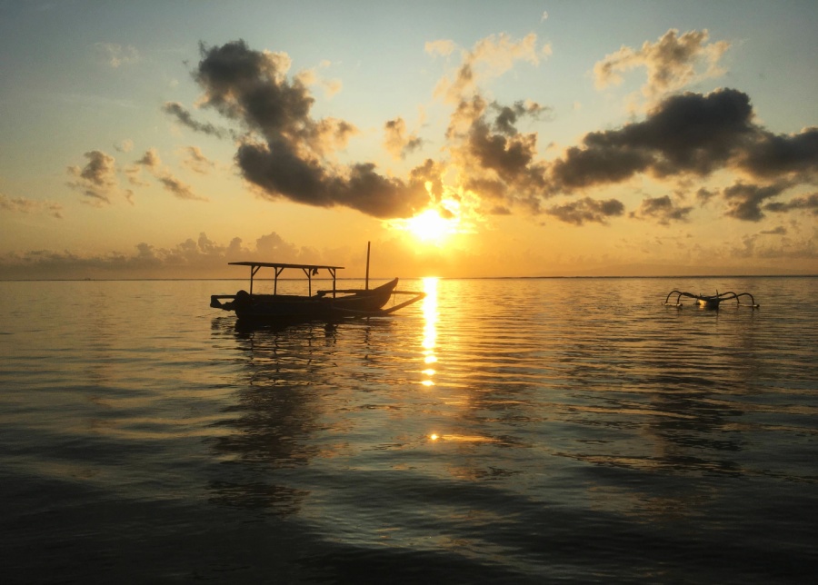 Traditional wooden boat sailing at sunrise from Sanur, Bali, Indonesia