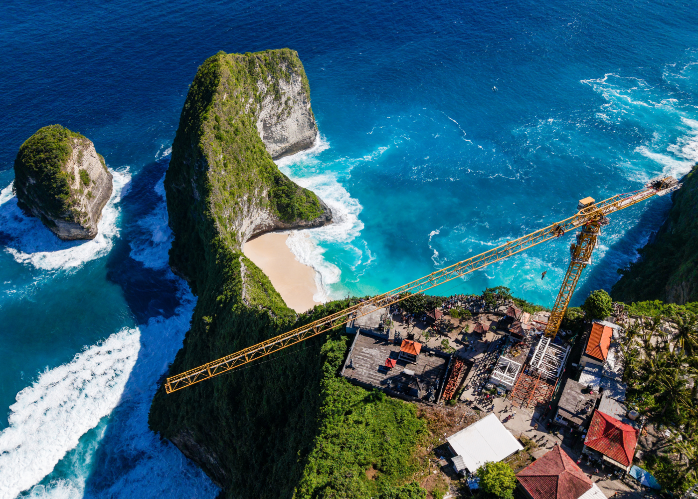 Close-up of a yellow construction crane on the cliffs of Kelingking Beach, Nusa Penida