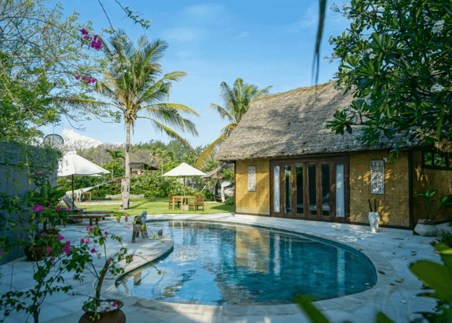 Private villa and curved swimming pool surrounded by palm trees at Pondok Santi Estate.