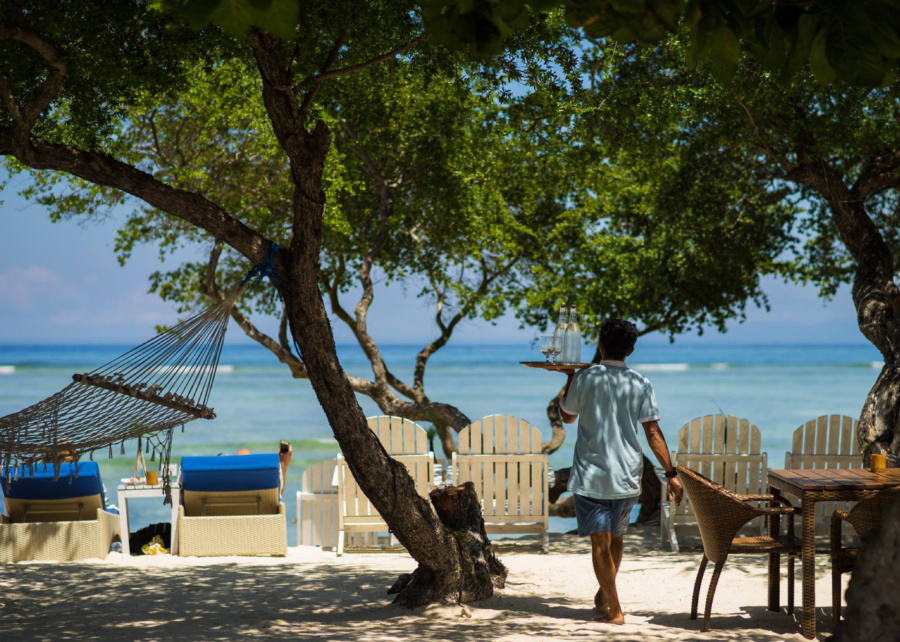 Beach tables, wooden chairs and sun loungers at Gili Teak Beach Club - where to eat in Gili Trawangan, Lombok, Indonesia, with ocean views