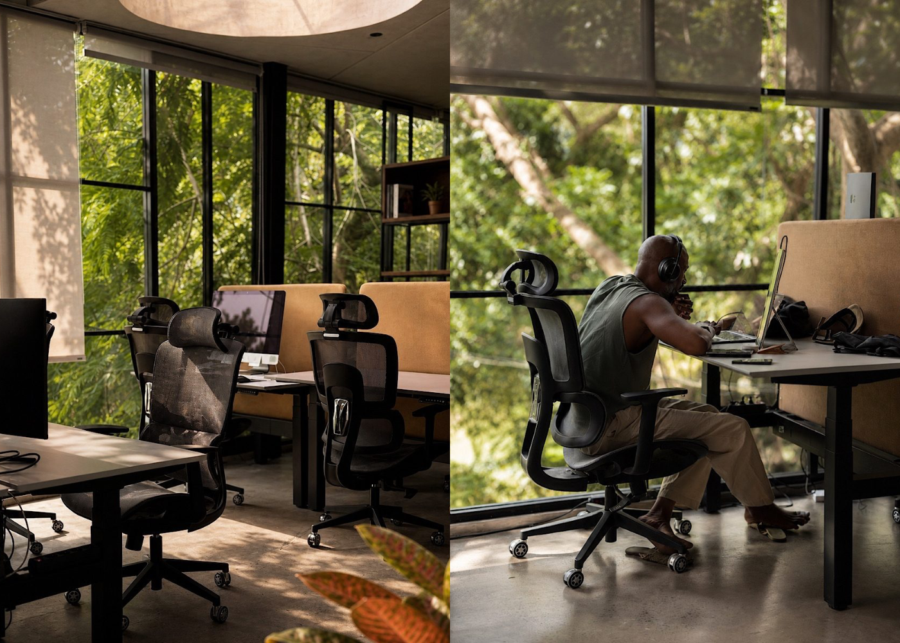 Coworking area at Hedonist Space in Ungasan, with ergonomic chairs, sit-stand desks and a man in headphones working on a laptop beside floor-to-ceiling windows.