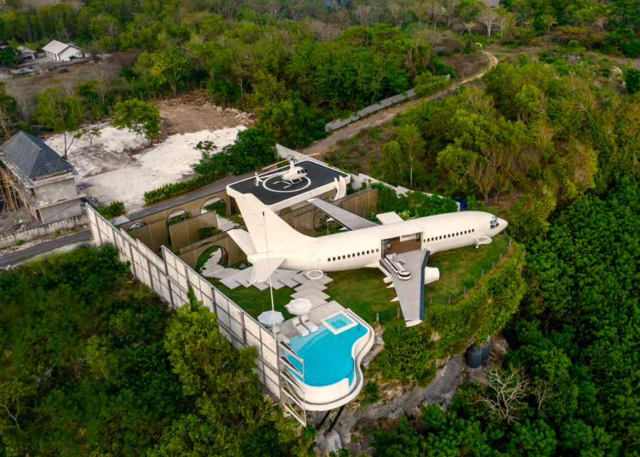 Aerial view of Private Jet Villa Uluwatu, a converted Boeing 737 villa perched on a cliff above Nyang Nyang Beach, featuring an infinity pool, helipad and panoramic ocean surroundings.