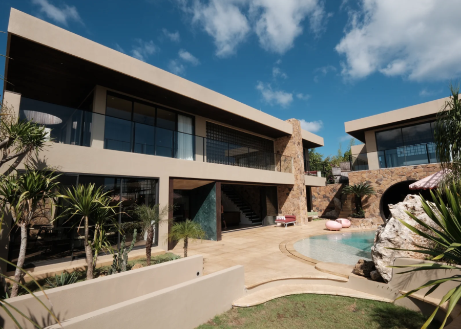 Slim Summer House in Bingin featuring modern Mediterranean-inspired architecture, curved pool, natural stone textures and tropical landscaping.