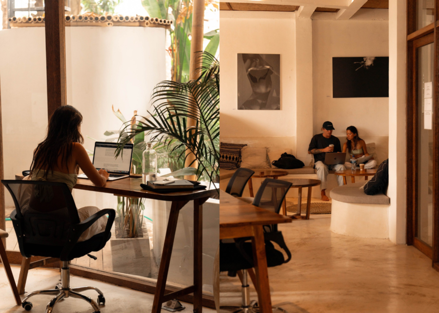 Interior of The Space Bingin coworking in Pecatu, with a woman working on a laptop at a wooden desk by the window and others relaxing on a sofa with coffee.