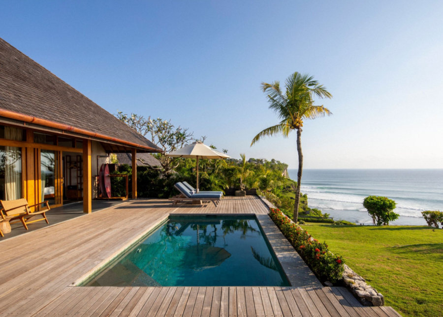 Private pool villa at Uluwatu Surf Villas overlooking Suluban Beach, featuring a wooden deck, tropical garden and sweeping Indian Ocean surf views from the clifftop.