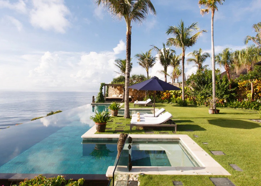Clifftop infinity pool at Villa Ambar, The Ungasan Clifftop Resort, featuring manicured lawns, sun loungers and panoramic Indian Ocean views from Uluwatu.