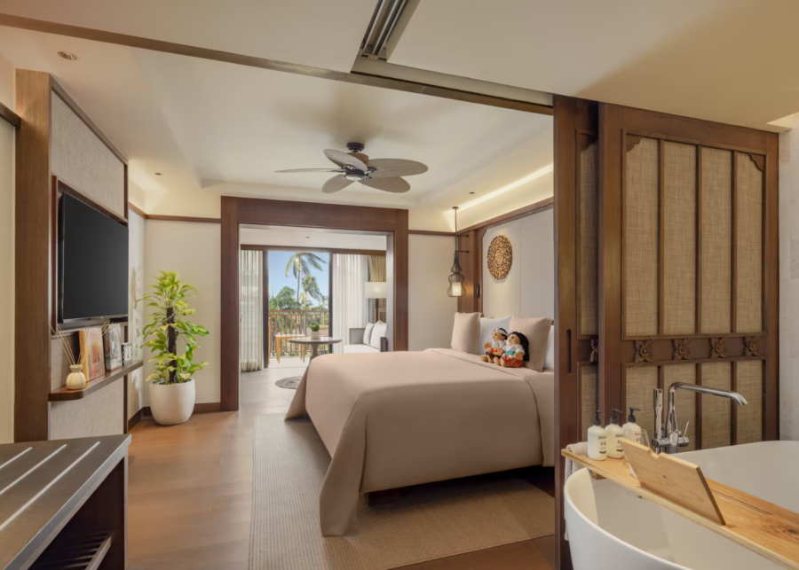 Spacious Junior Suite at Paradisus by Meliá Bali in Nusa Dua, featuring warm wood interiors, a king-sized bed, sliding balcony doors with palm views and an in-room soaking bathtub.