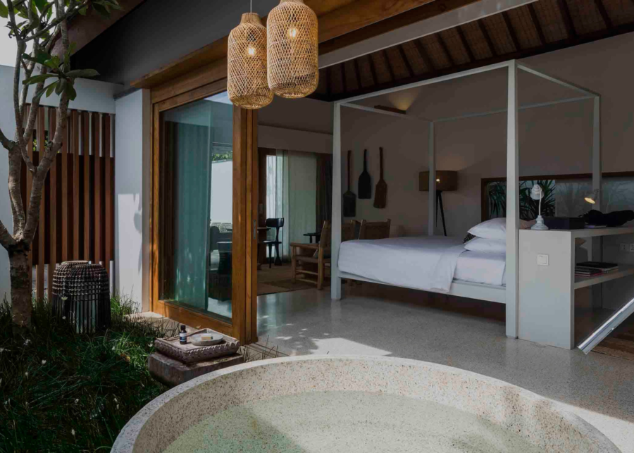 Open-plan pavilion bedroom at Mandarin Oriental Exceptional Home in Uluwatu, featuring a four-poster bed and floor-to-ceiling sliding glass doors