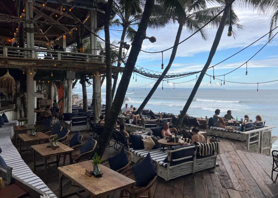 La Brisa Canggu beachfront venue with rustic wooden decks, lounge seating, palm trees and ocean views.