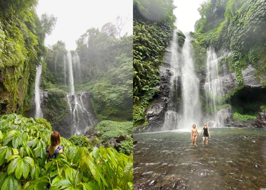 Lush jungle view of Sekumpul and Fiji Waterfalls with multiple streams cascading down steep cliffs, and two people standing in the pool beneath the falls.