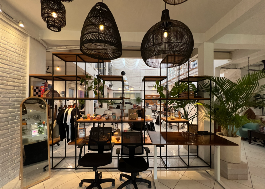 Tropical Nomad Canggu co-working space with wooden desks, black shelving, woven pendant lights and indoor greenery.