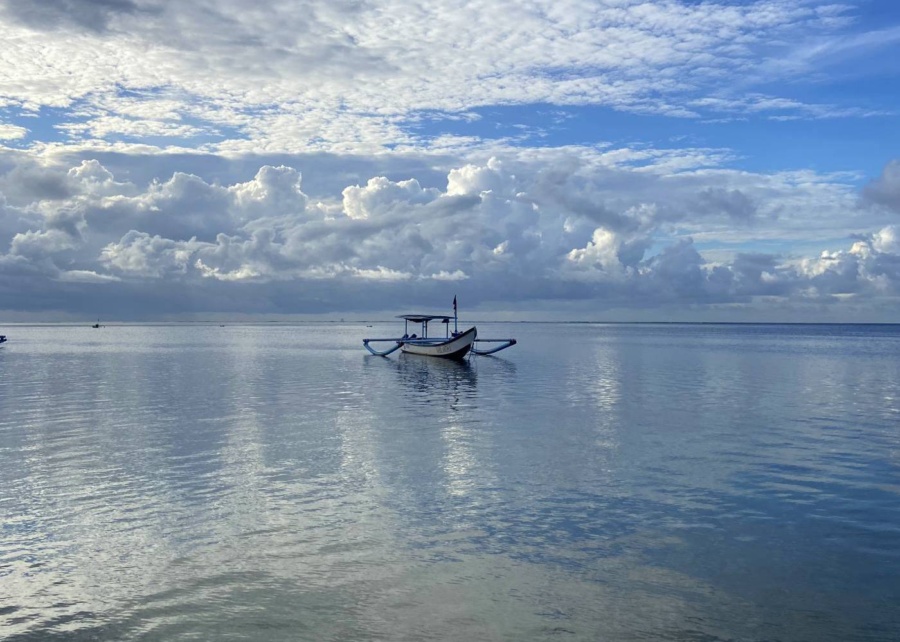 wooden fishing boat floating offshore from Sanur Beach in Bali, Indonesia