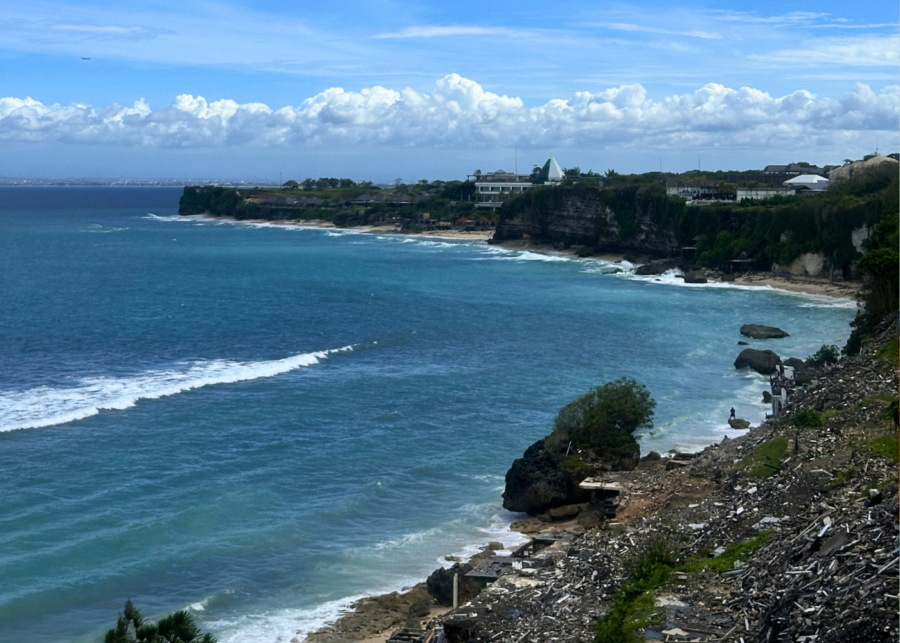 View over Bingin Beach in Uluwatu, Bali, with surf rolling in and demolition debris at the base of the cliff.
