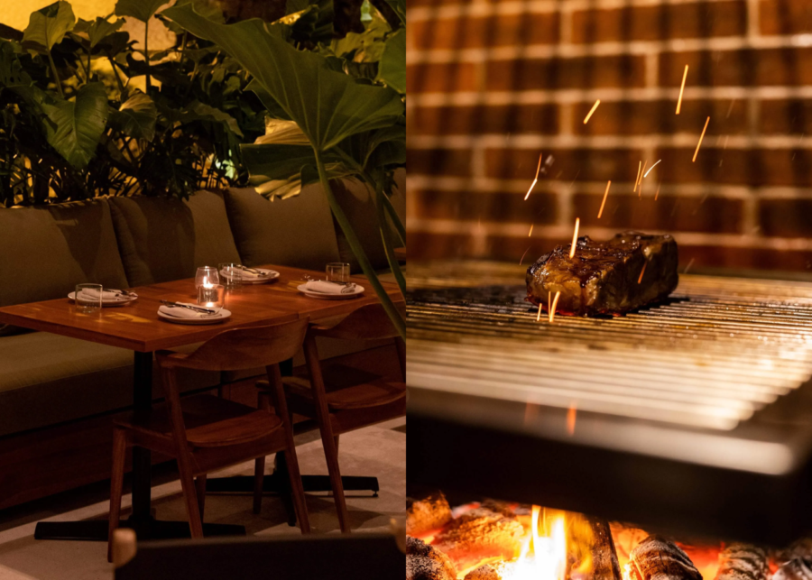 asonry Uluwatu's low-lit dining room with a candlelit table and banquette under tropical plants, beside a steak searing over a wood-fired grill.