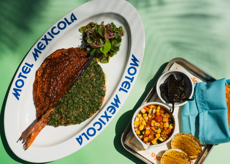 Whole grilled snapper on a Motel Mexicola platter, half topped with red salsa and half with green salsa verde, served with charred chillies, corn salad and tortillas.