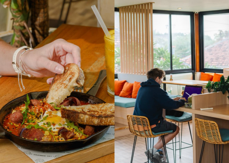 A man working on a laptop at a rattan bar stool by the window at Granary Cafe and Workspace in Seminyak, with a skillet baked-egg breakfast and a juice on a table in the foreground.
