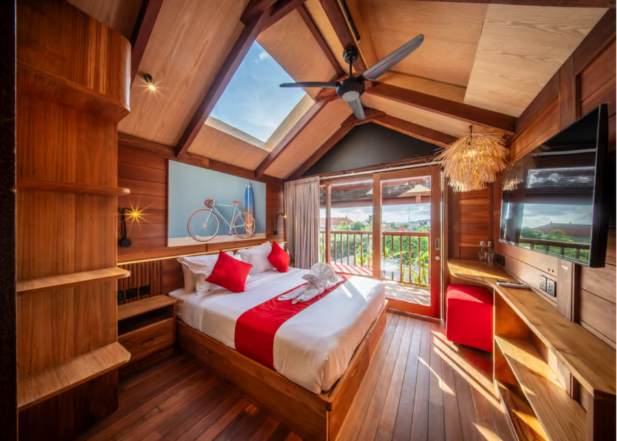 The Wooden Rooftop Balcony Room at SOKKOOL coliving in Canggu, Bali, with a timber A-frame ceiling, a skylight and a balcony overlooking Berawa.
