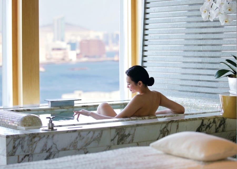 woman bathing in marble tub spa room with sea view