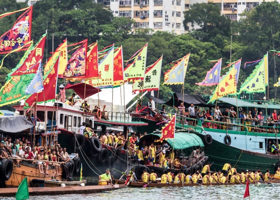 dragon boats colourful flags hong kong sea houses buildings people crowds