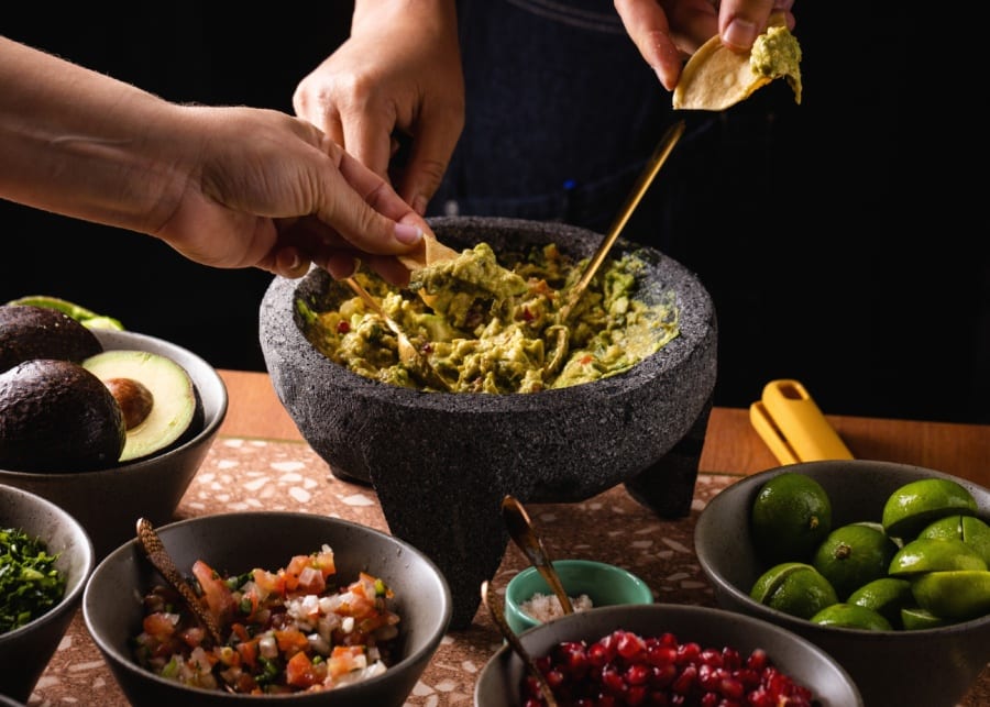 tableside guacamole ingredients fresh avocado three hands dipping nachos