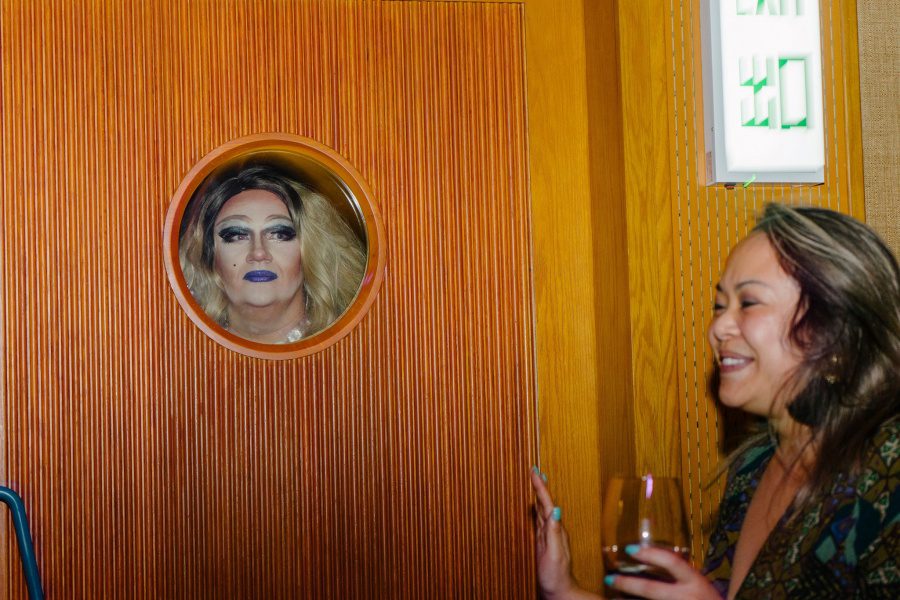 a drag queen looking through a door