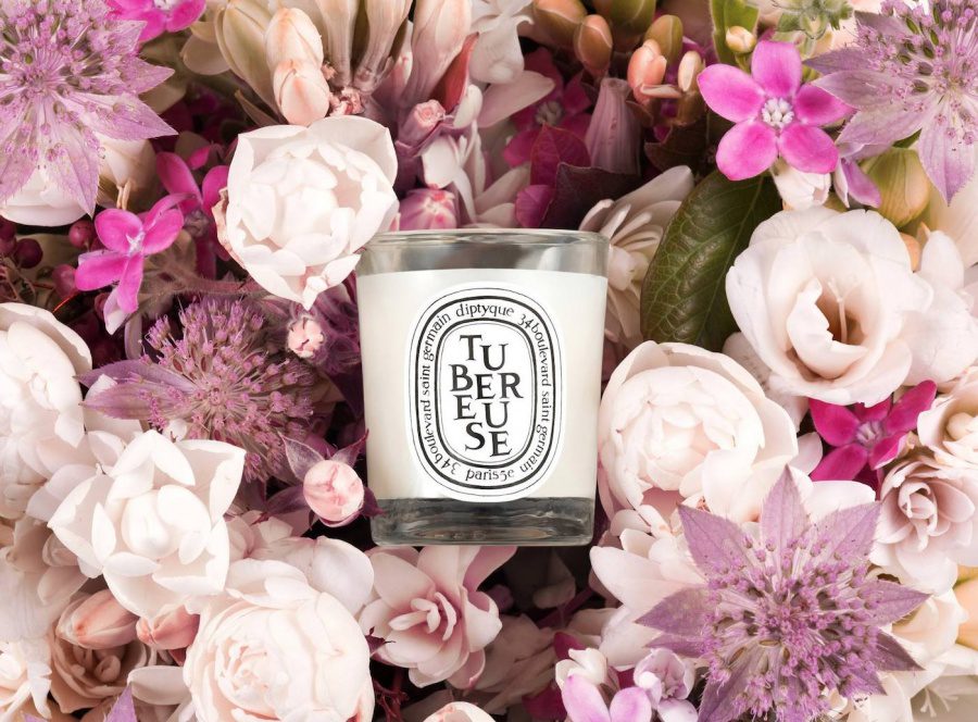 a candle jar surrounded by pink and white flowers
