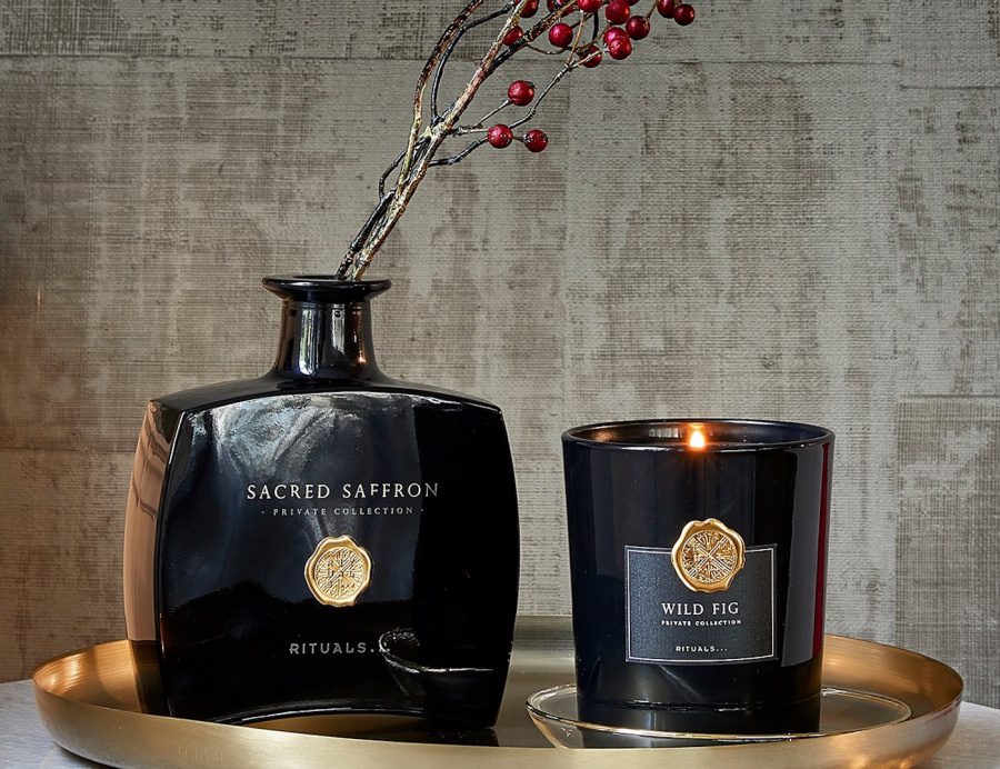 a black candle jar and a fragrance stick bottle with some flowers